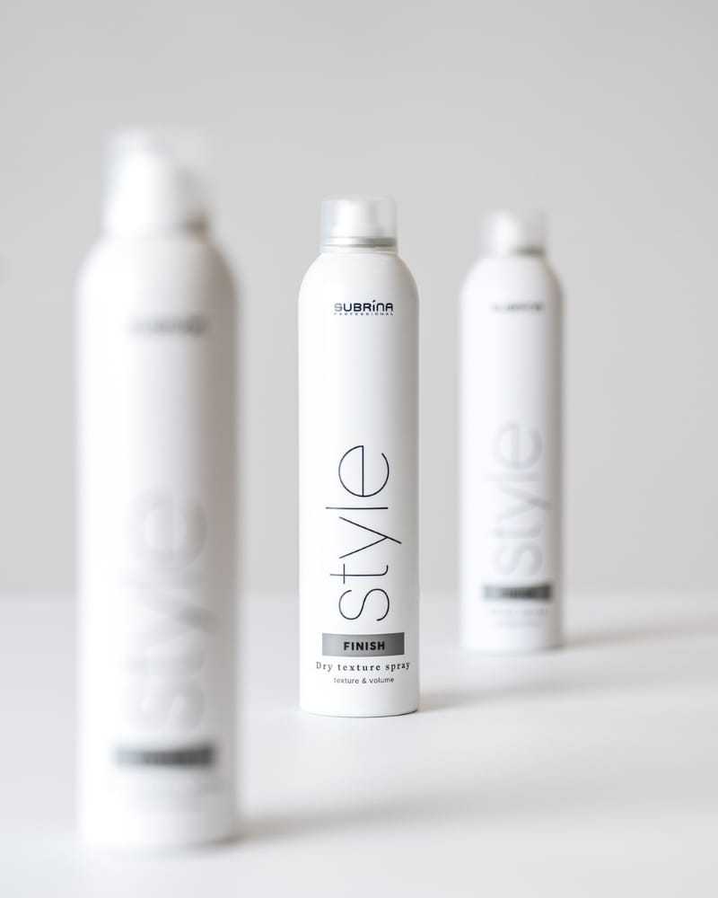 Three bottles of hair styling spray with minimalist design on a white background.