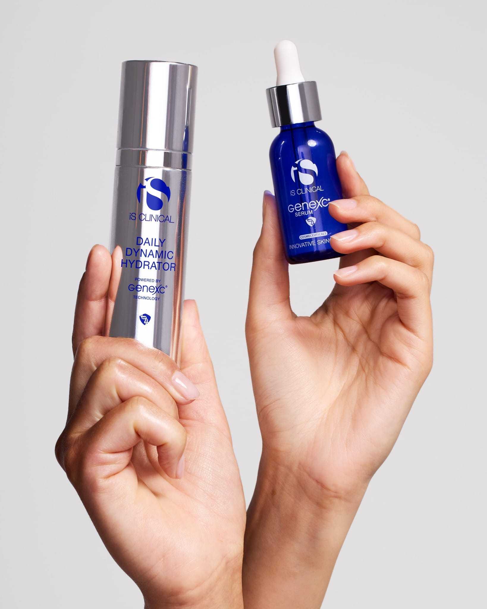 Hands holding skincare products with blue bottles and silver packaging.